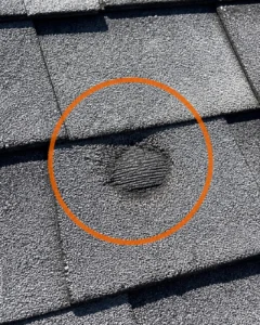 Close-up of hail damage bruise on asphalt shingle highlighted during DFW roof repair inspection