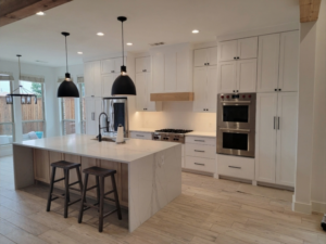 White shaker kitchen remodel in Frisco, TX with waterfall-edge island, white oak accents, and professional gas range